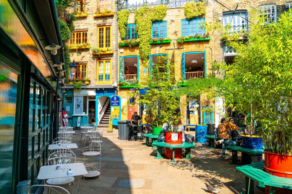 A vibrant courtyard with colorful buildings, lush greenery, outdoor seating, and people enjoying the lively atmosphere.