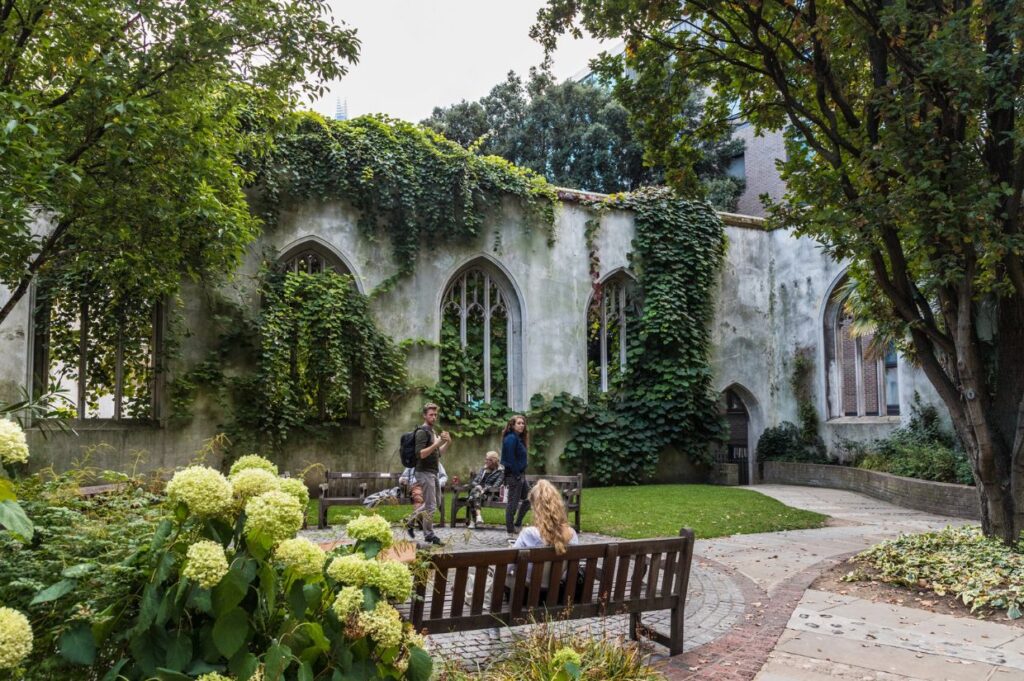 The ruins of St. Dunstan-in-the-East church in London, now a peaceful garden with ivy-covered Gothic arches.