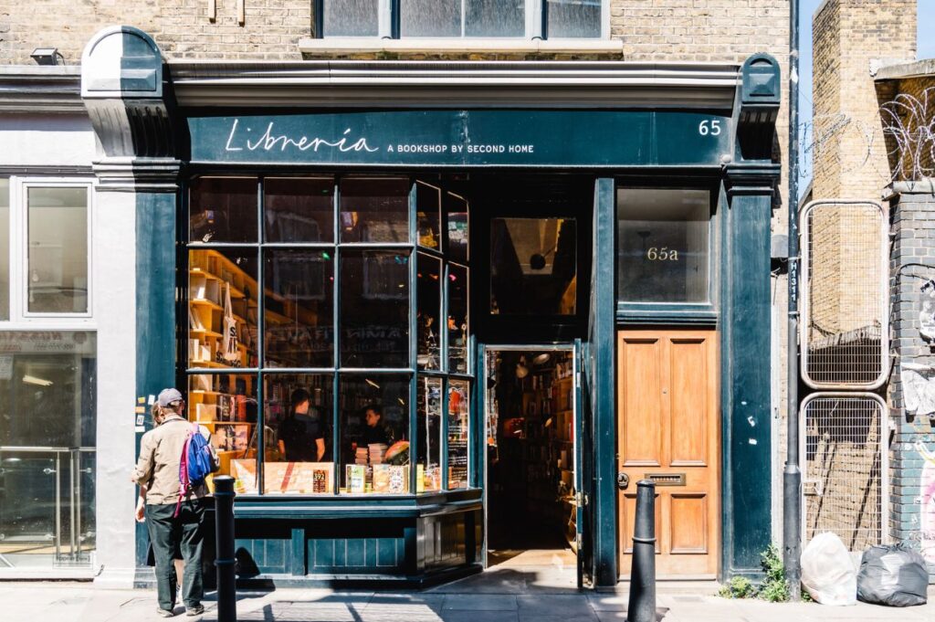 A charming bookshop, Libreria, features large glass windows filled with colorful books, inviting passersby to explore.