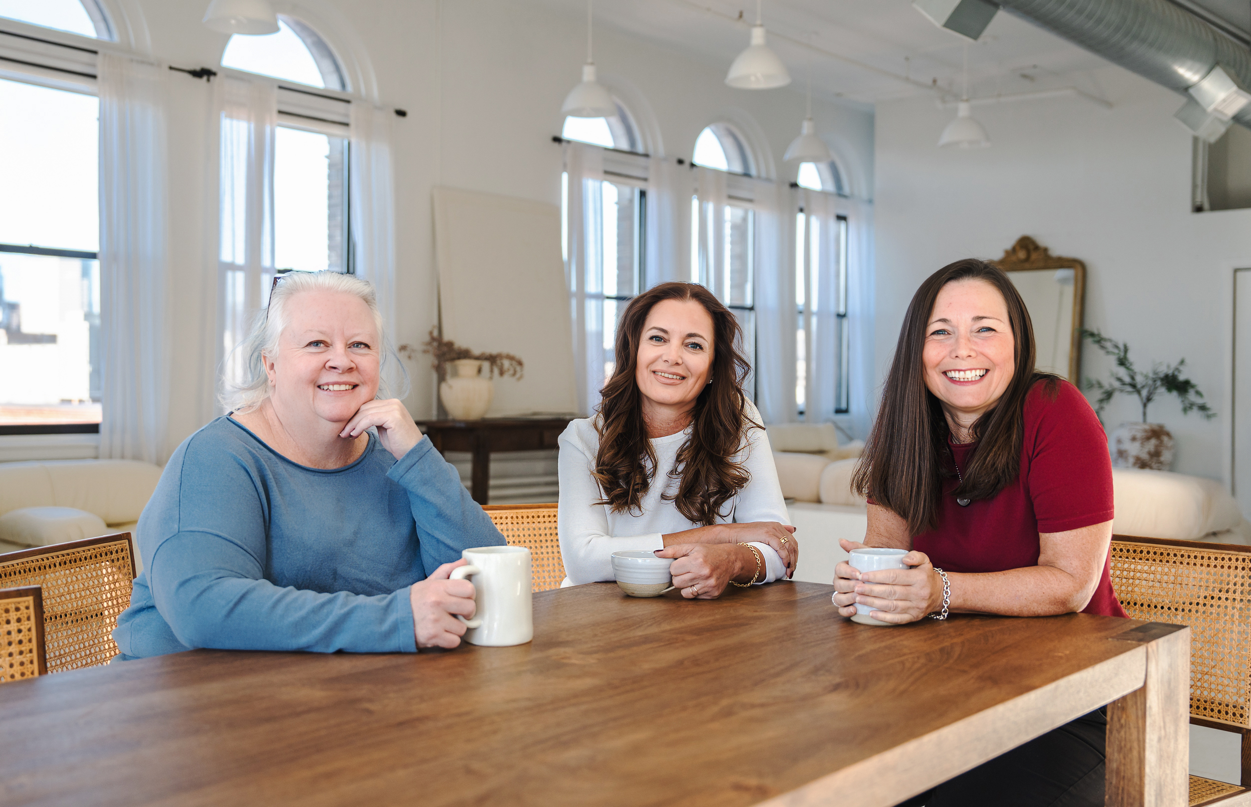 The three website founders sitting together at a table smiling.