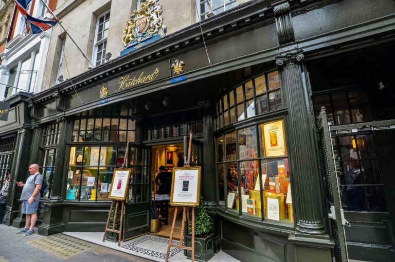 A historic bookshop with a dark green façade and large curved windows displaying books.
