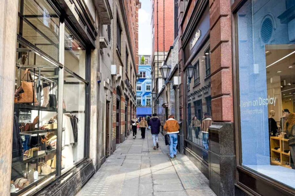 Brydges Place, one of London’s narrowest alleyways, is shown tucked between tall brick buildings, creating a tight, atmospheric passageway.