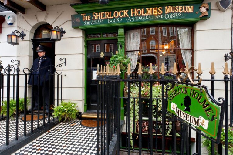 Exterior of the Sherlock Holmes Museum in London, featuring a uniformed guard standing by the iconic 221B Baker Street door, with green signage and vintage-style decor.